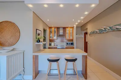 a kitchen with a large island with two bar stools at Hermanus Marine Square spacious 1 bedroom- central & close to sea in Hermanus