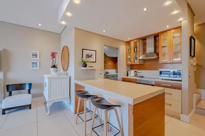 a kitchen with a counter and stools at Hermanus Marine Square spacious 1 bedroom- central & close to sea in Hermanus