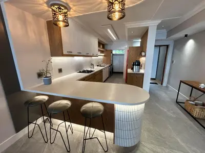 a kitchen with a white counter and stools at Bayview 107 in Hermanus