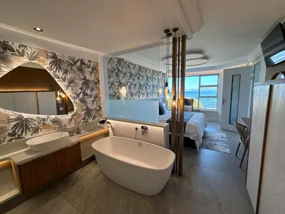 a bathroom with a tub and a bedroom with a bed at Bayview 107 in Hermanus