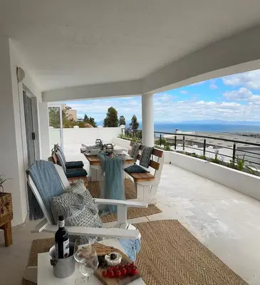 a living room with a table and a view of the ocean at Coral Vistas Self Catering Apartments in Gordonʼs Bay