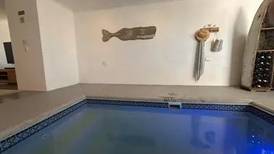 a swimming pool in a room with a fish on the wall at Coral Vistas Self Catering Apartments in Gordonʼs Bay