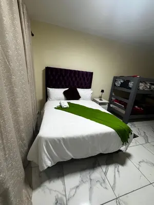 a bedroom with a bed with a green blanket on it at Kitty Guest House in Bellville