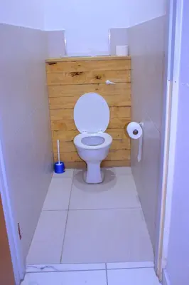 a bathroom with a toilet with a wooden wall at Kitty Guest House in Bellville