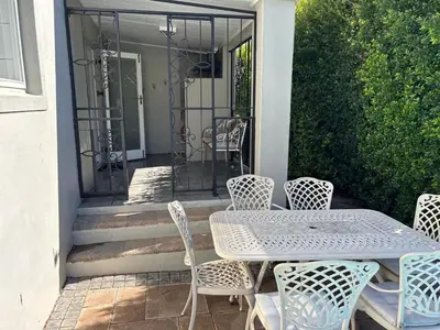 a patio with a table and chairs and a gate at Lemon Tree Cottage a Charming 3 Bedroom Self-catering house in Franschhoek