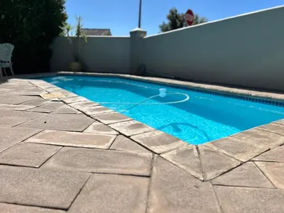 a small swimming pool in a backyard with a stone patio at Lemon Tree Cottage a Charming 3 Bedroom Self-catering house in Franschhoek