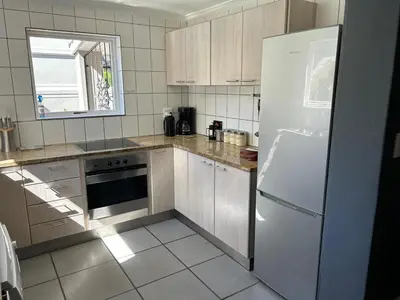a kitchen with a white refrigerator and a window at Lemon Tree Cottage a Charming 3 Bedroom Self-catering house in Franschhoek