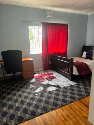 a bedroom with a bed and a red curtain at Comfort Guest House in Tiervlei