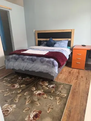 a bedroom with a bed and a rug on the floor at Comfort Guest House in Tiervlei