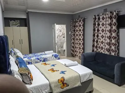 a bedroom with two beds and a blue couch at Gift Guest house 2 in Cravenby