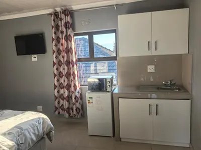 a small kitchen with white cabinets and a window at Gift Guest house 1 in Cravenby