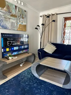 a living room with a blue couch and a tv at Cottage in Cape Town