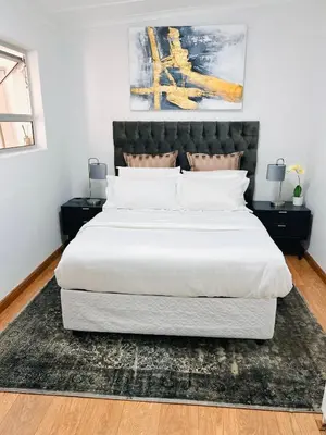 a bedroom with a large white bed with a black headboard at Cottage in Cape Town