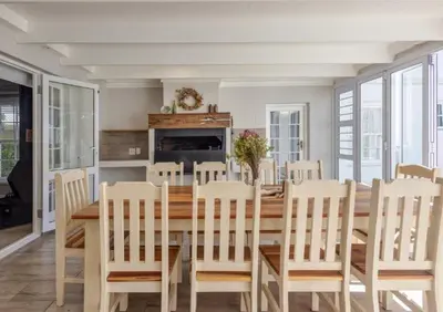 a dining room with a wooden table and chairs at Beachcomber's Rest in Hermanus