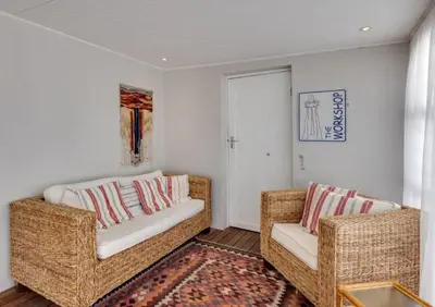 a living room with two wicker couches and a rug at Beachcomber's Rest in Hermanus