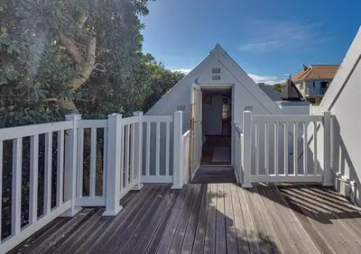 a wooden deck with a white fence and a door at Beachcomber's Rest in Hermanus