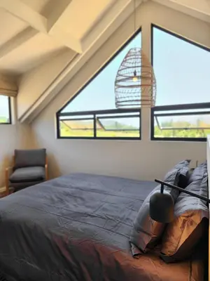 a bedroom with a bed and a chair and a window at Breedekloof Kajuit in Romansrivier