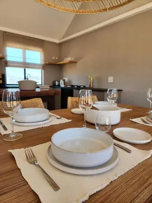 a wooden table with plates and wine glasses on it at Breedekloof Kajuit in Romansrivier