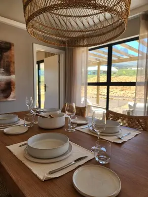 a wooden table with plates and wine glasses on it at Breedekloof Kajuit in Romansrivier