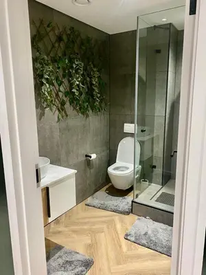 a bathroom with a toilet and a plant on the wall at On Park Century City Cozy Apartment in Cape Town