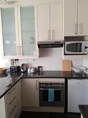 a kitchen with white cabinets and a stove top oven at Studio 5 at Huis Piron in Stellenbosch
