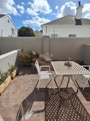a patio with a table and a white table and chair at Studio 5 at Huis Piron in Stellenbosch