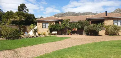 a house with a grass yard in front of it at Protea-Sabr in Sir Lowry Pass
