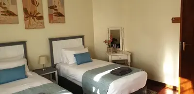 a bedroom with two beds and a mirror at Protea-Sabr in Sir Lowry Pass