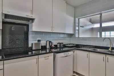 a kitchen with white cabinets and stainless steel appliances at Gordonia Unit 9 Gordons Bay in Gordonʼs Bay