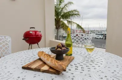 a table with a bowl of bread and a glass of wine at Gordonia Unit 9 Gordons Bay in Gordonʼs Bay