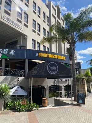 a building with a restaurant with a palm tree in front of it at The Protea & Vine - Paarl - Self Catering Apartment in Paarl