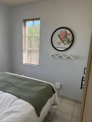 a bedroom with a bed and a mirror on the wall at The Protea & Vine - Paarl - Self Catering Apartment in Paarl