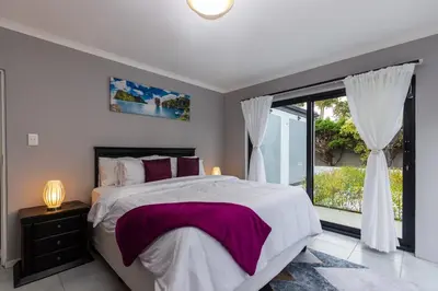 a bedroom with a large bed and a large window at Winelands Escape in Durbanville