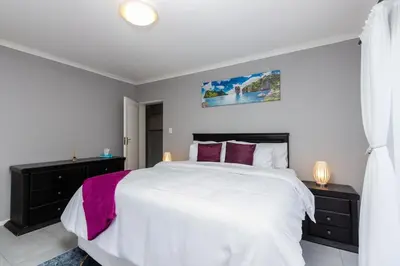 a bedroom with a large white bed with purple pillows at Winelands Escape in Durbanville