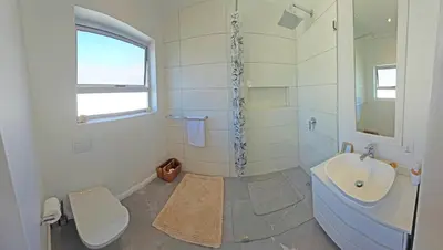 a white bathroom with a sink and a toilet at Cape Town Studio Apartment in Cape Town