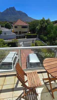 a balcony with two chairs and a table and a car at Cape Town Studio Apartment in Cape Town