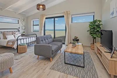 a living room with a couch a chair and a tv at Nature's Nest in Bettyʼs Bay