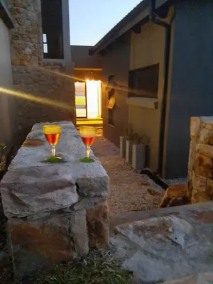 two wine glasses sitting on top of a stone wall at Nature's Nest in Bettyʼs Bay