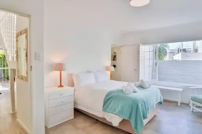a white bedroom with a bed and a window at Vonkelwyn - enjoy Grotto Beach sunsets in Hermanus