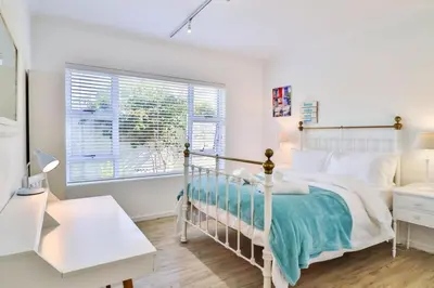 a white bedroom with a bed and a window at Vonkelwyn - enjoy Grotto Beach sunsets in Hermanus