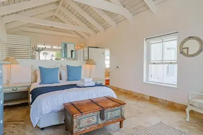 a bedroom with a large bed with blue pillows at Nautilus on Grotto Beach - heated pool in Hermanus
