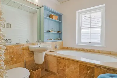 a bathroom with a tub and a sink and a toilet at Nautilus on Grotto Beach - heated pool in Hermanus