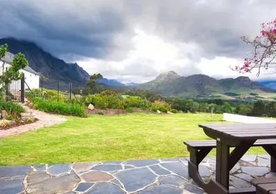 a picnic table in a field with mountains in the background at Wildeberg Elephants Trail Cottage in Franschhoek