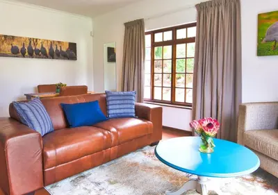 a living room with a brown leather couch and a table at Wildeberg Elephants Trail Cottage in Franschhoek