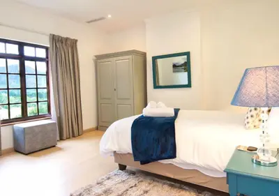a bedroom with a bed and a desk and a window at Wildeberg Elephants Trail Cottage in Franschhoek