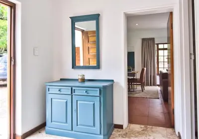 a blue cabinet in a hallway with a mirror at Wildeberg Elephants Trail Cottage in Franschhoek