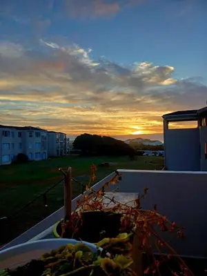 a view of the sunset from the balcony of a building at Beach Club 150 Hermanus in Hermanus