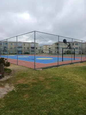 a tennis court in front of a building at Beach Club 150 Hermanus in Hermanus