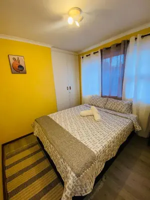 a bedroom with a bed and a yellow wall at GWMV Guest House in Cape Town