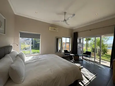 a bedroom with a large bed and large windows at La Vita Farm Stay in Wellington